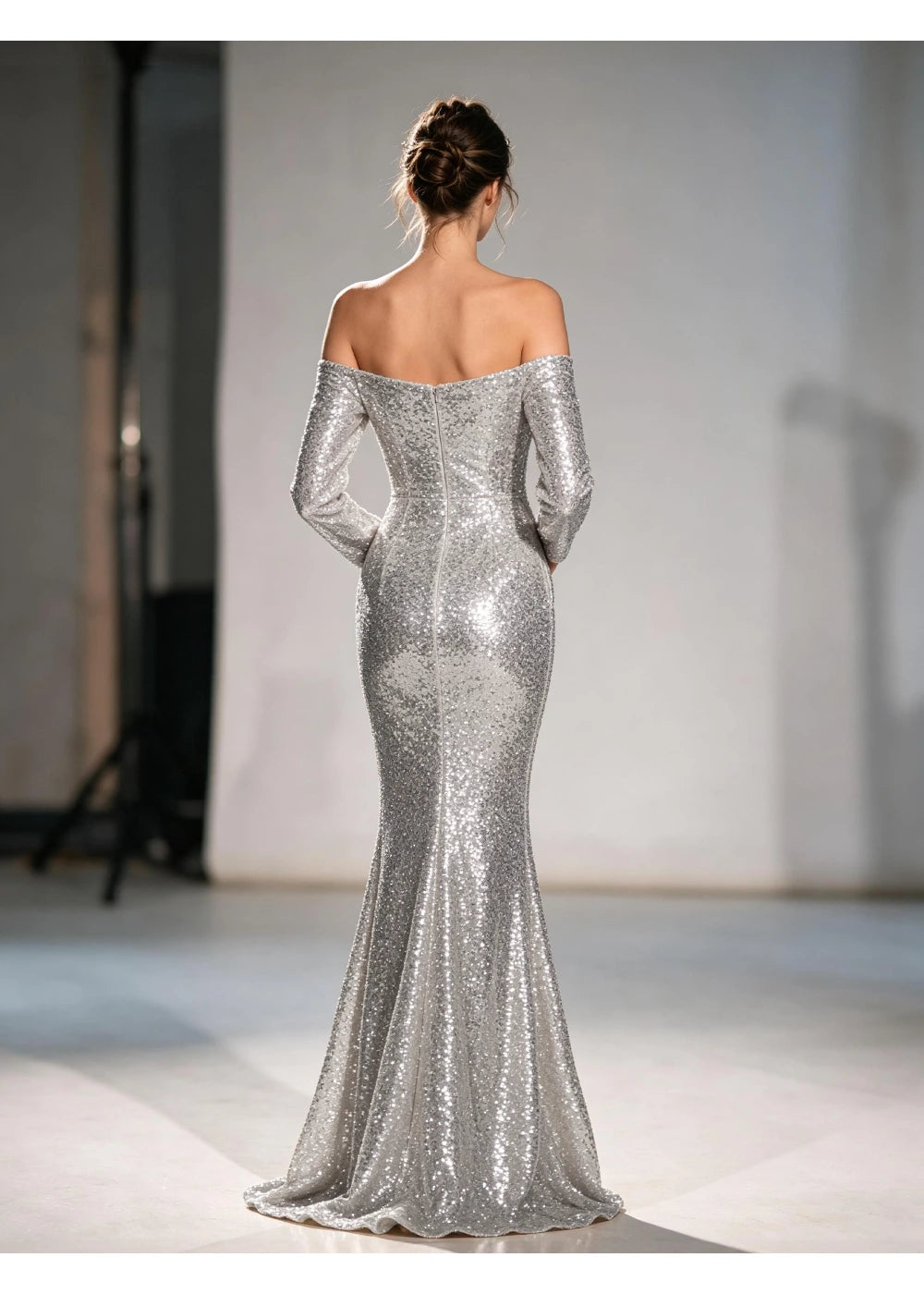 Back view of the silver sequin gown showing the bare shoulder line and fitted mermaid skirt