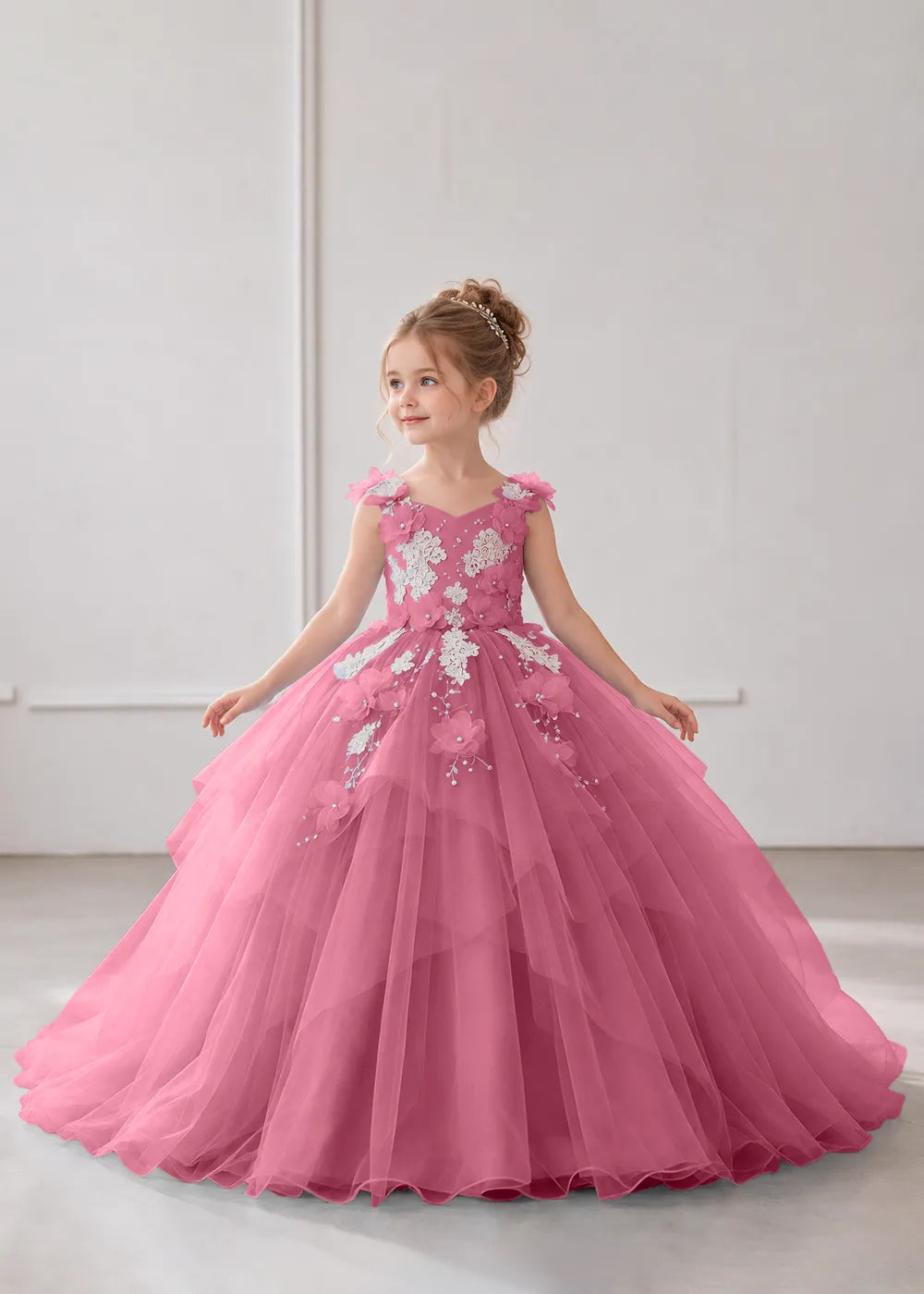 Front view of a child wearing a desert rose flower girl dress with a V-neckline, floral shoulder appliques and lace and flower decoration across the bodice and hips.