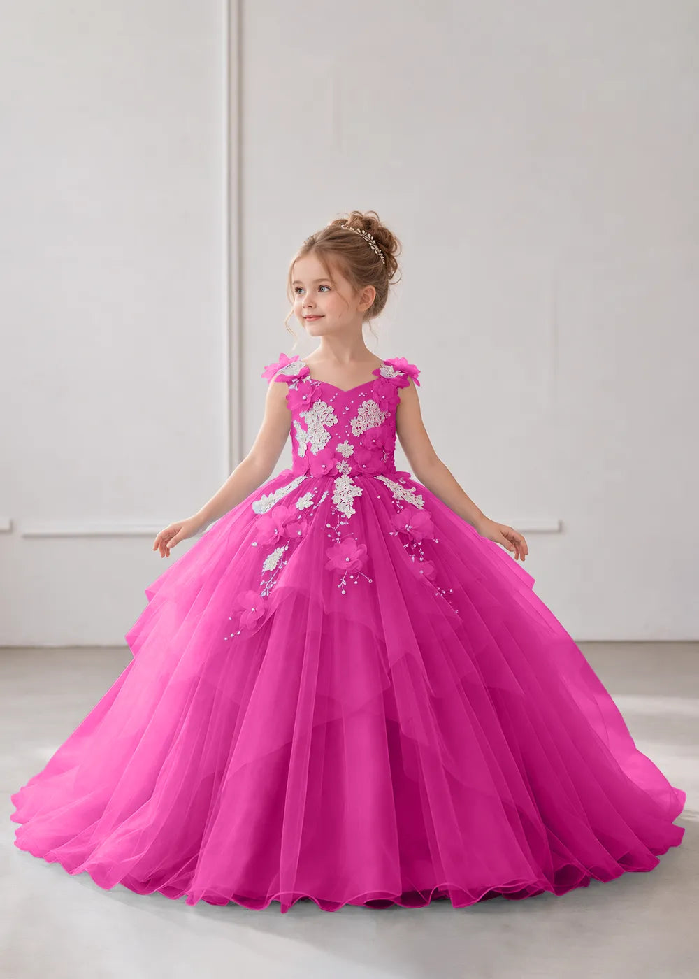 Front view of a child wearing a hot pink flower girl dress with a V-neckline, floral shoulder appliques and lace and flower decoration across the bodice and hips.