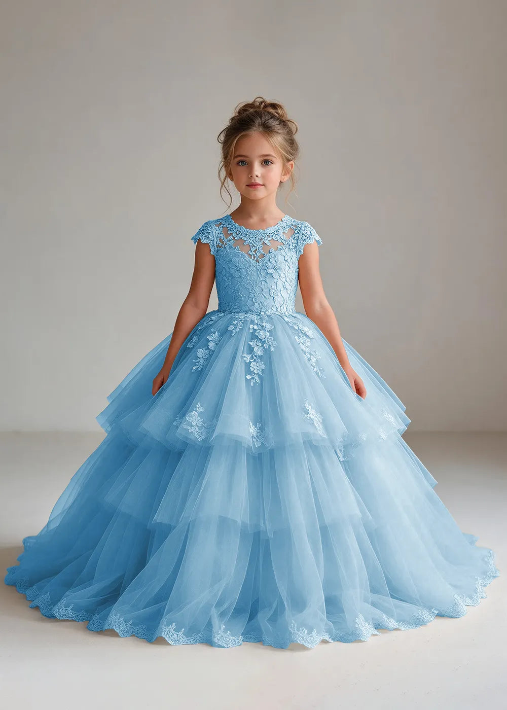 Front view of a child wearing a light blue flower girl dress with a sheer lace illusion neckline, cap sleeves and a tiered cake-style tulle skirt with a lace-trimmed hem.