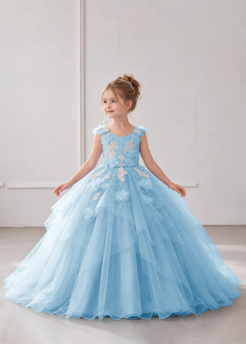 Front view of a child wearing a light blue flower girl dress with a V-neckline, floral shoulder appliques and lace and flower decoration across the bodice and hips.