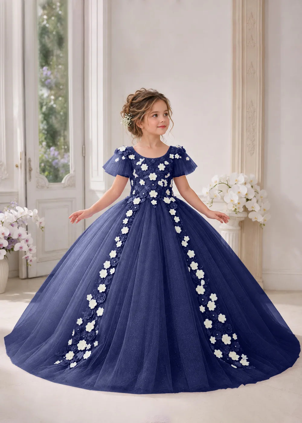 Front view of a child wearing a navy blue flower girl dress with a round neckline, sheer flutter cap sleeves and a floral vine cascading down both sides of a full tulle skirt.