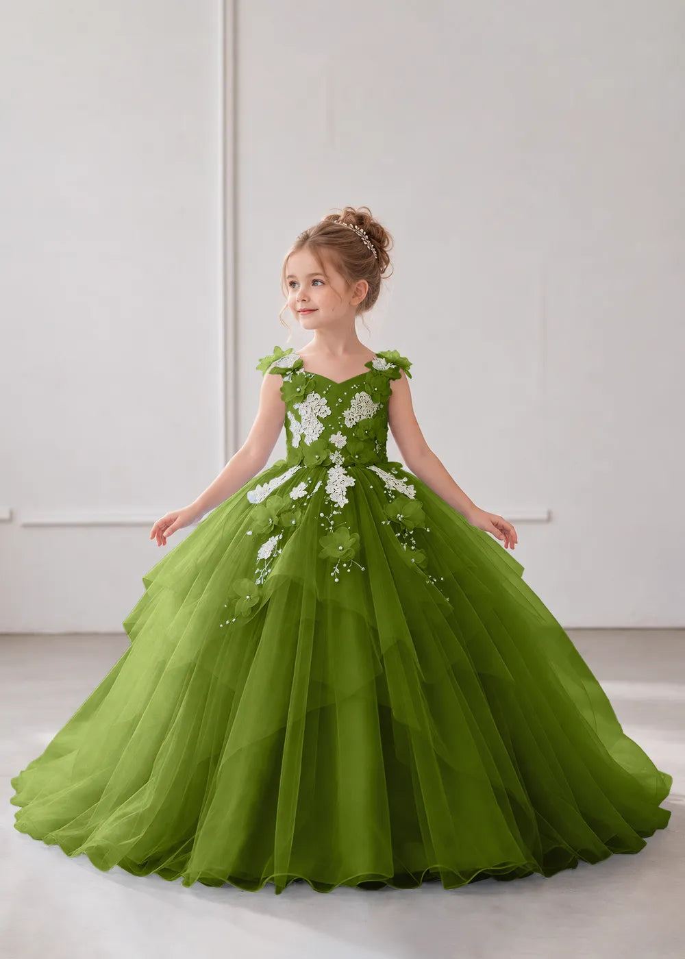 Front view of a child wearing a olive flower girl dress with a V-neckline, floral shoulder appliques and lace and flower decoration across the bodice and hips.