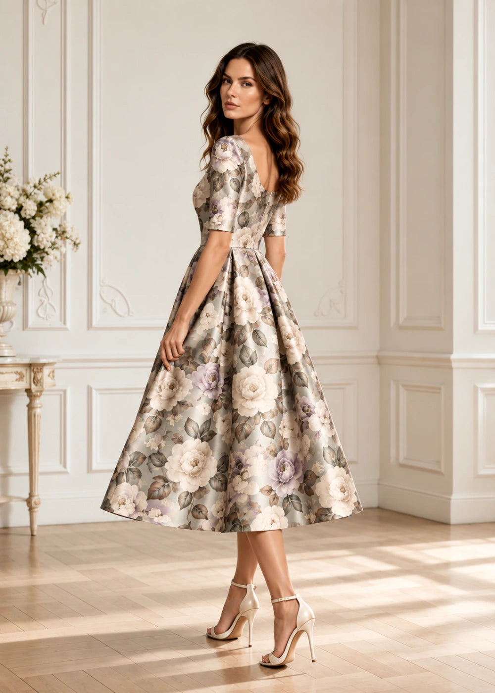 Left side and front three-quarter view of a champagne botanical A-line midi dress showing the elbow sleeve, defined waist, and full skirt