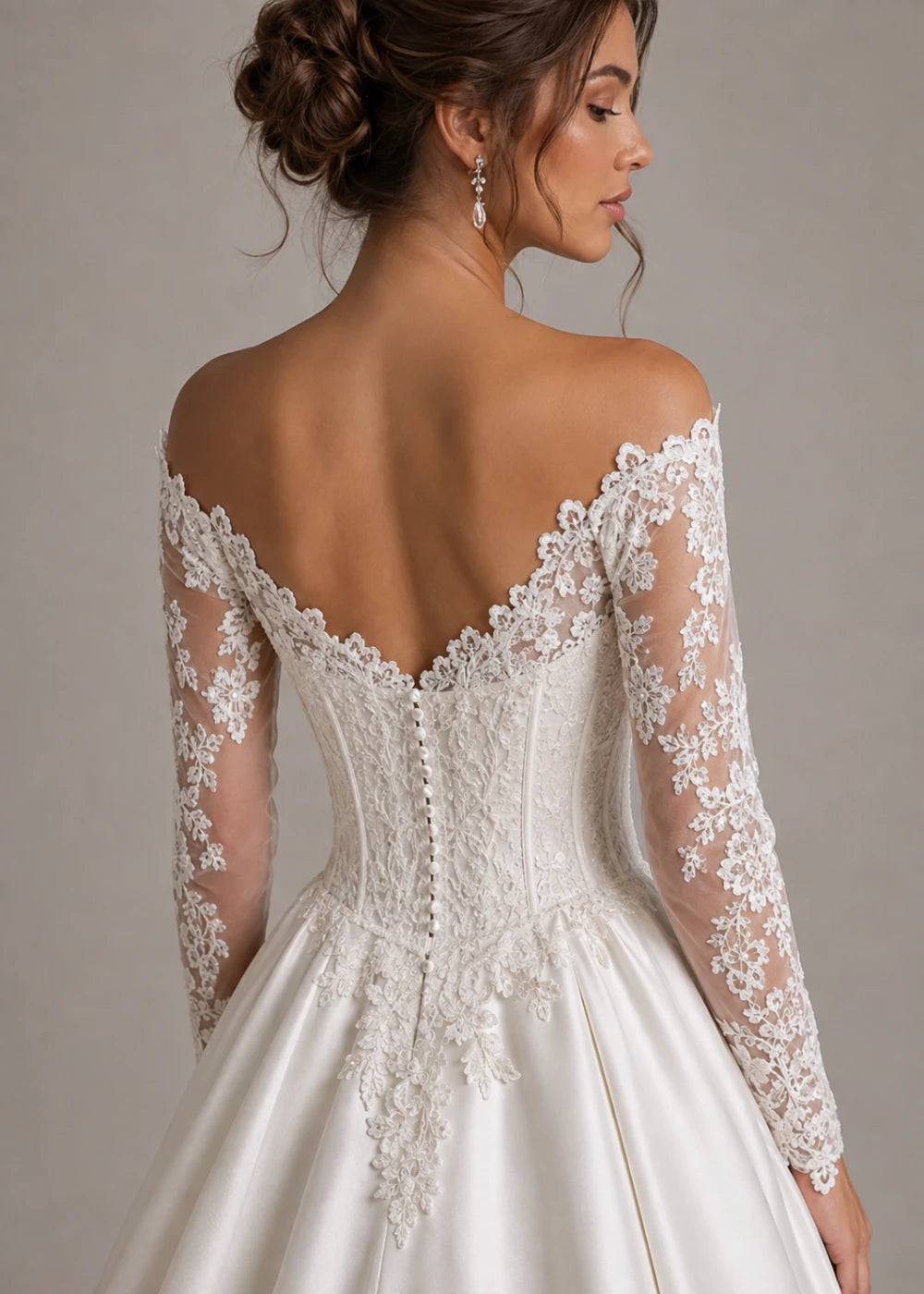 Back detail of an ivory ball gown showing the deep backline, lace sleeves, and fitted waist