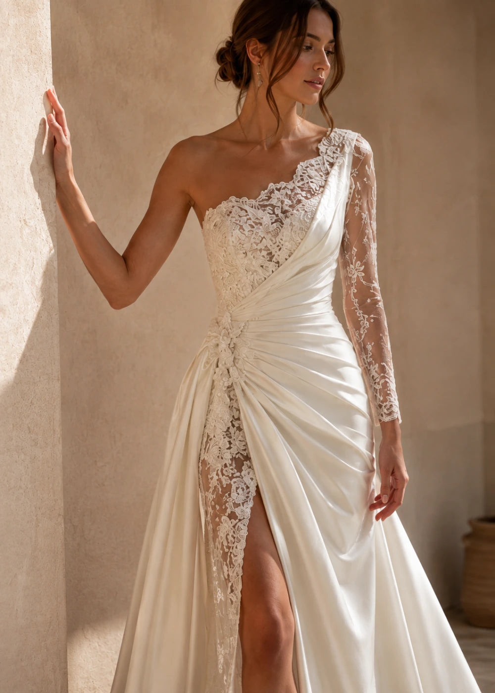 Detail view of the ivory one-shoulder fitted gown with one long lace sleeve, a thigh-high slit, and a train