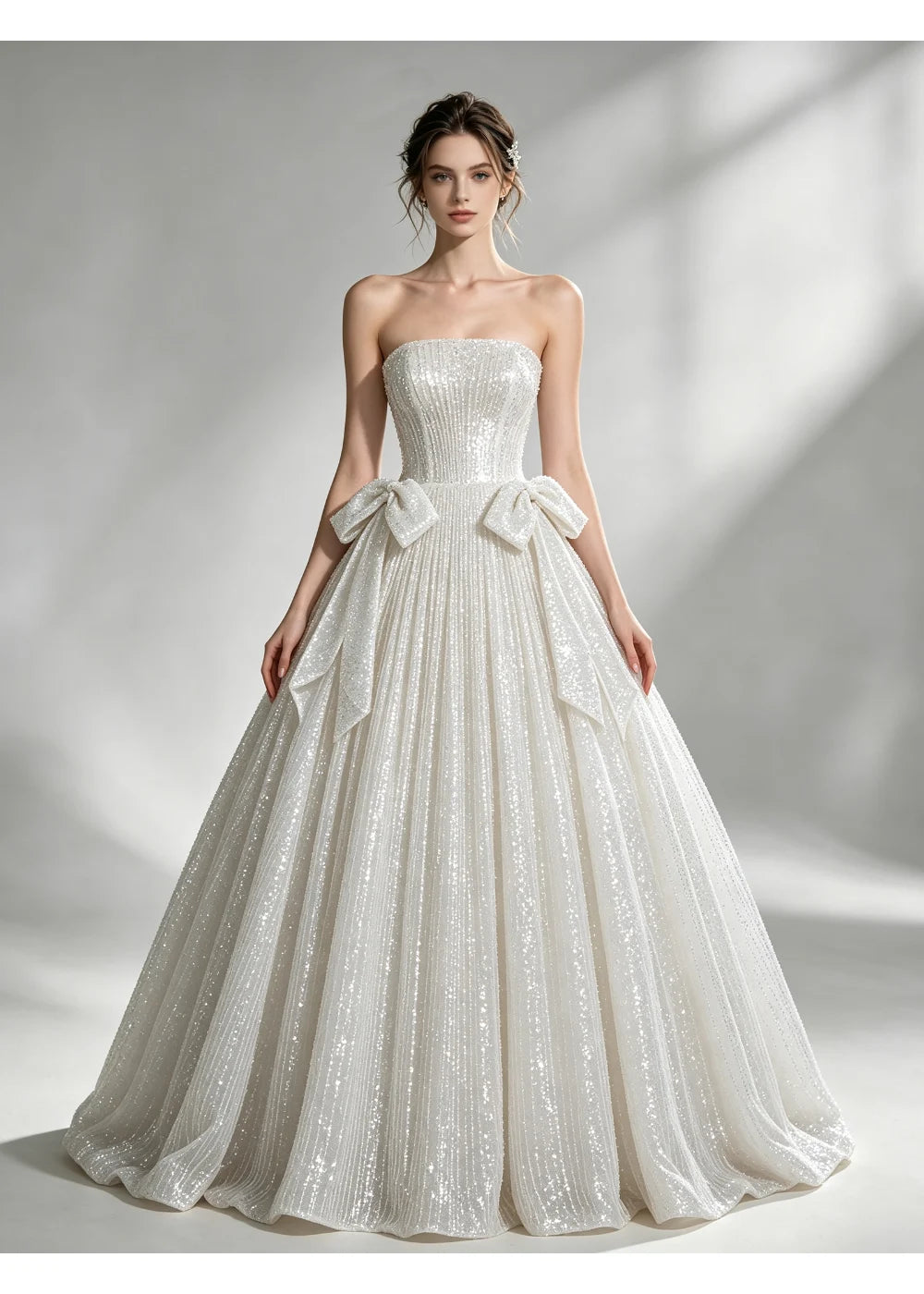 Front view of an ivory strapless sequin A-line gown with two bows at the waist