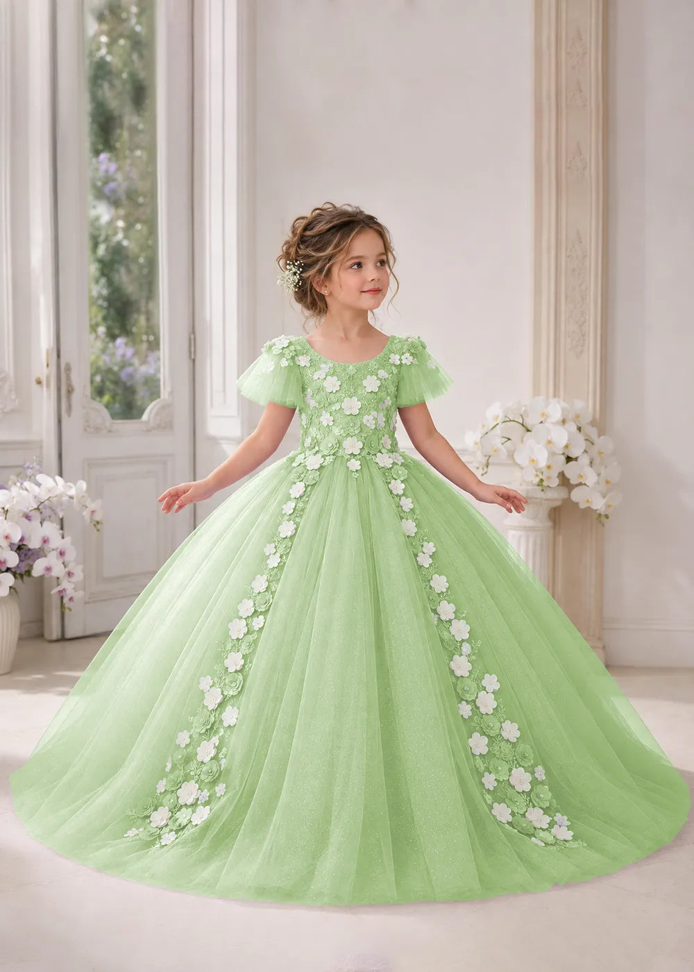 Front view of a child wearing a dusty sage flower girl dress with a round neckline, sheer flutter cap sleeves and a floral vine cascading down both sides of a full tulle skirt.