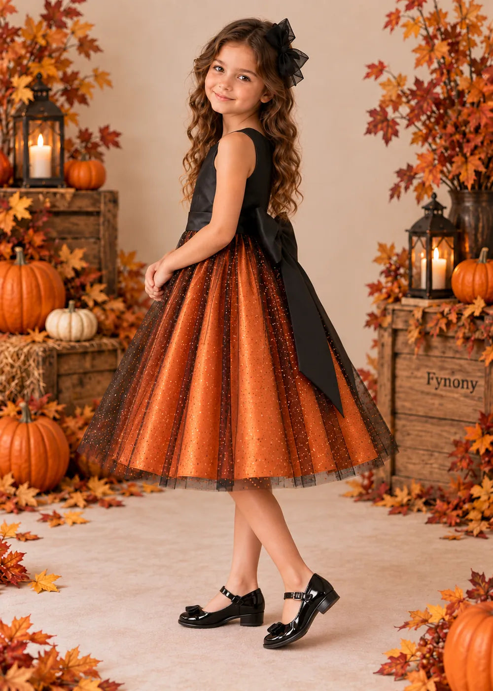 Rear three-quarter view of the sleeveless orange and black dress with the black bow against the full orange skirt.