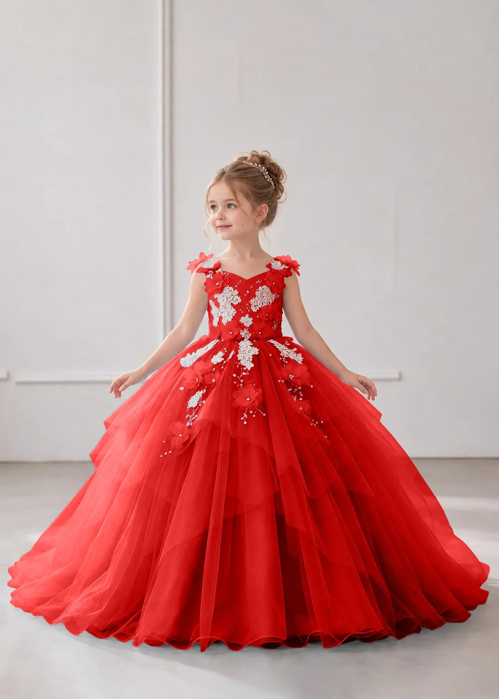 Front view of a child wearing a red flower girl dress with a V-neckline, floral shoulder appliques and lace and flower decoration across the bodice and hips.