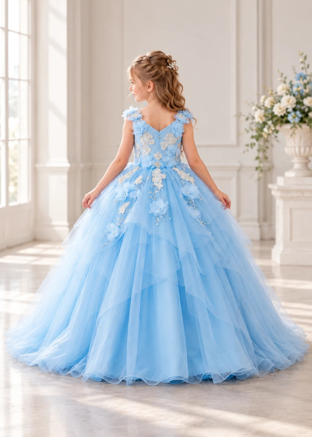 Rear view of a child wearing a sky blue flower girl dress with a V-neckline, floral shoulder appliques and lace and flower decoration across the bodice and hips.