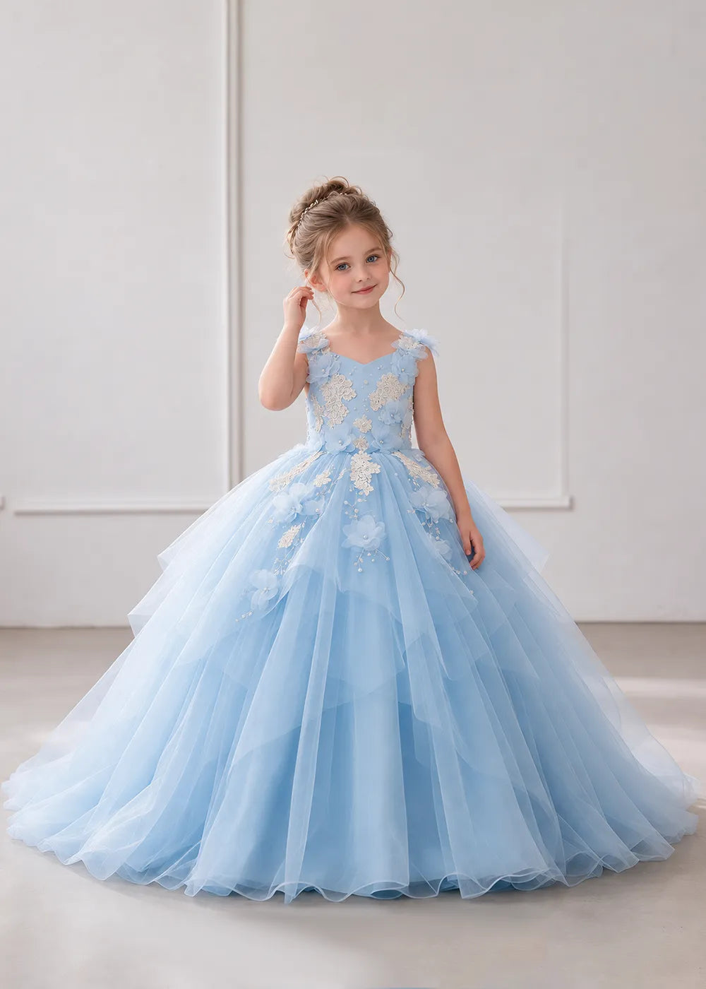 The three-quarter view of a child wearing a Sky Blue flower girl dress with a V-neckline, floral shoulder appliques and lace and flower decoration across the bodice and hips.