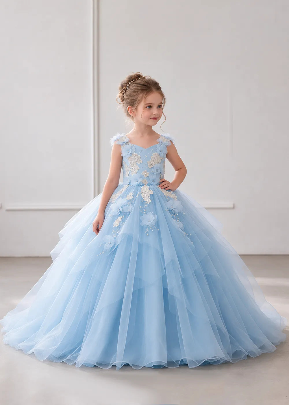 The front view of a child wearing a Sky Blue flower girl dress with a V-neckline, floral shoulder appliques and lace and flower decoration across the bodice and hips.