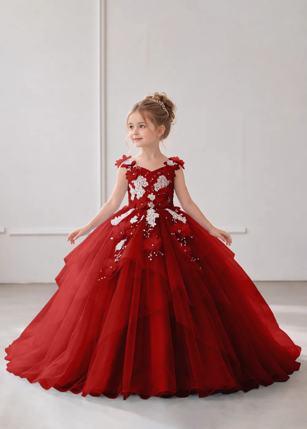 Front view of a child wearing a wine red flower girl dress with a V-neckline, floral shoulder appliques and lace and flower decoration across the bodice and hips.
