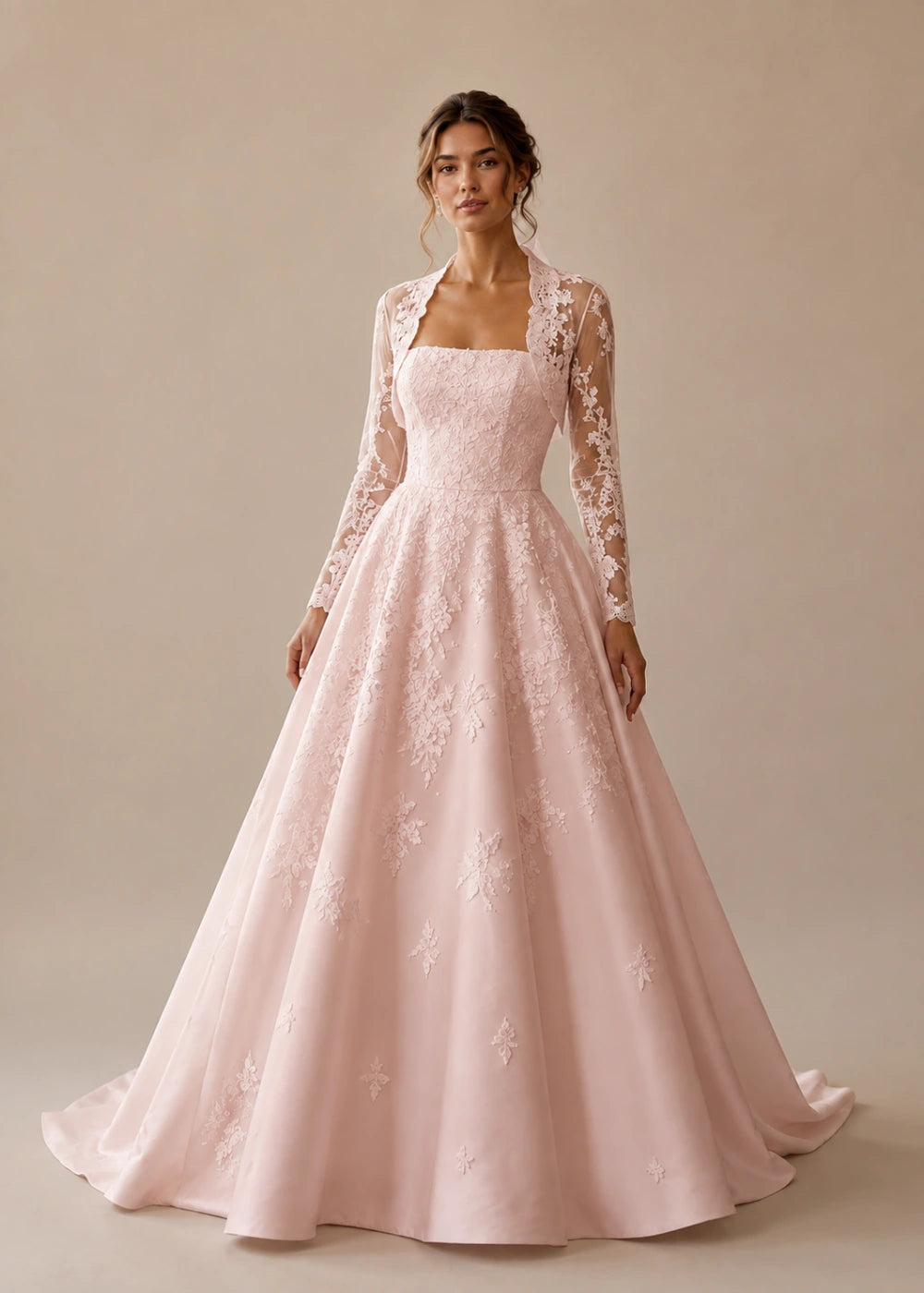 Front view of the blush pink square-neck A-line gown with a long-sleeve lace bolero-style overlay