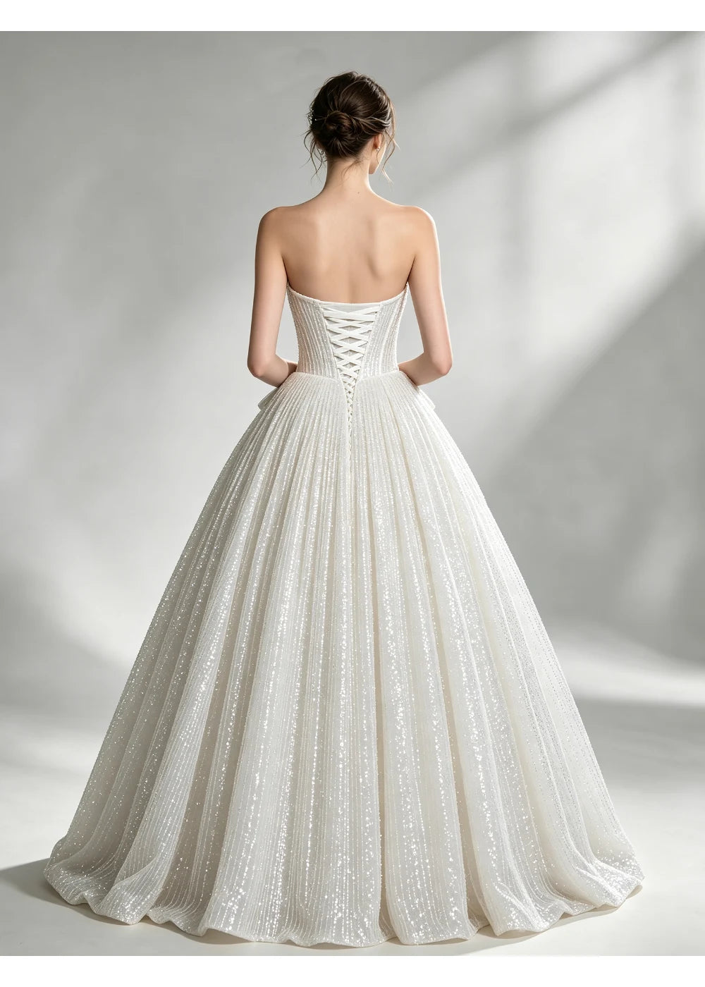 Back view of the ivory sequin gown showing crisscross lacing above a full skirt