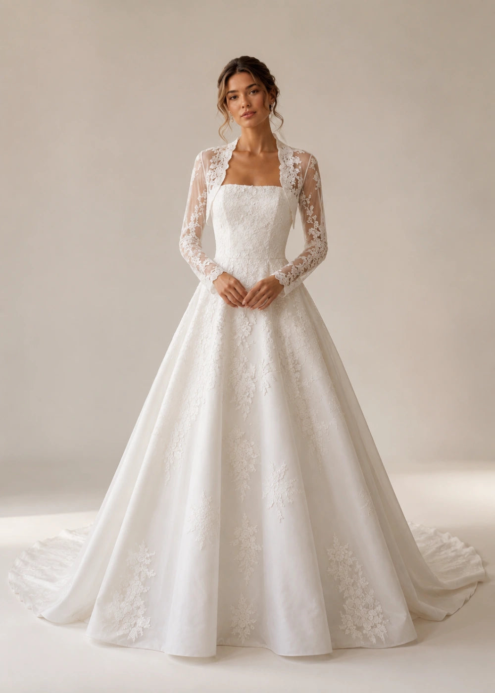 Front view of the ivory square-neck A-line gown with a long-sleeve lace bolero-style overlay