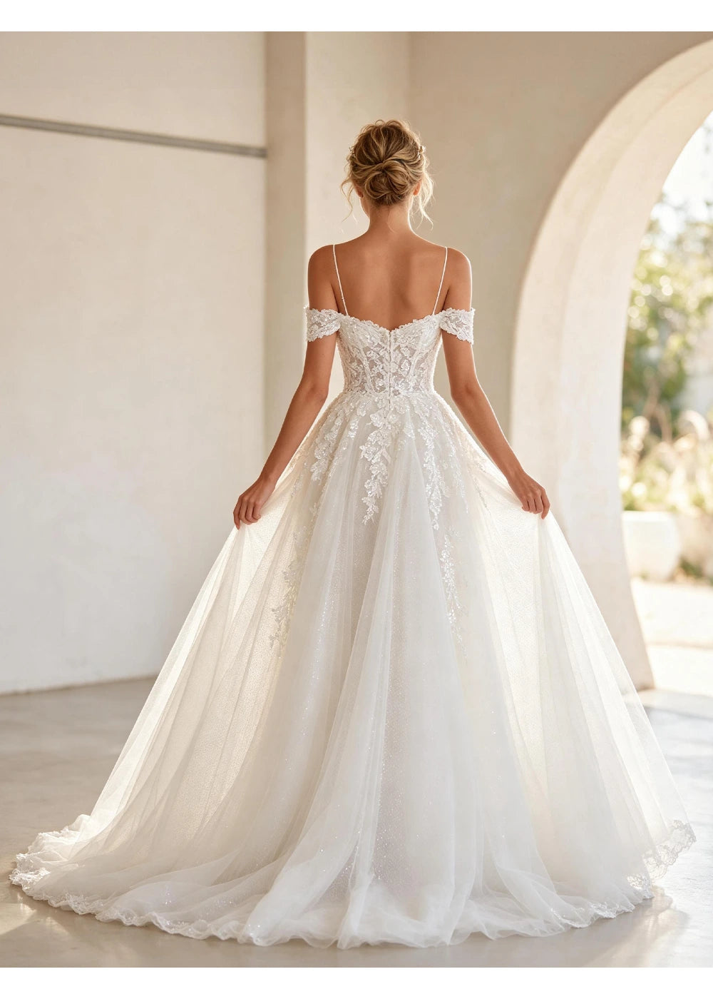 Back view of the white gown showing open shoulders, short lace bands and a trailing skirt